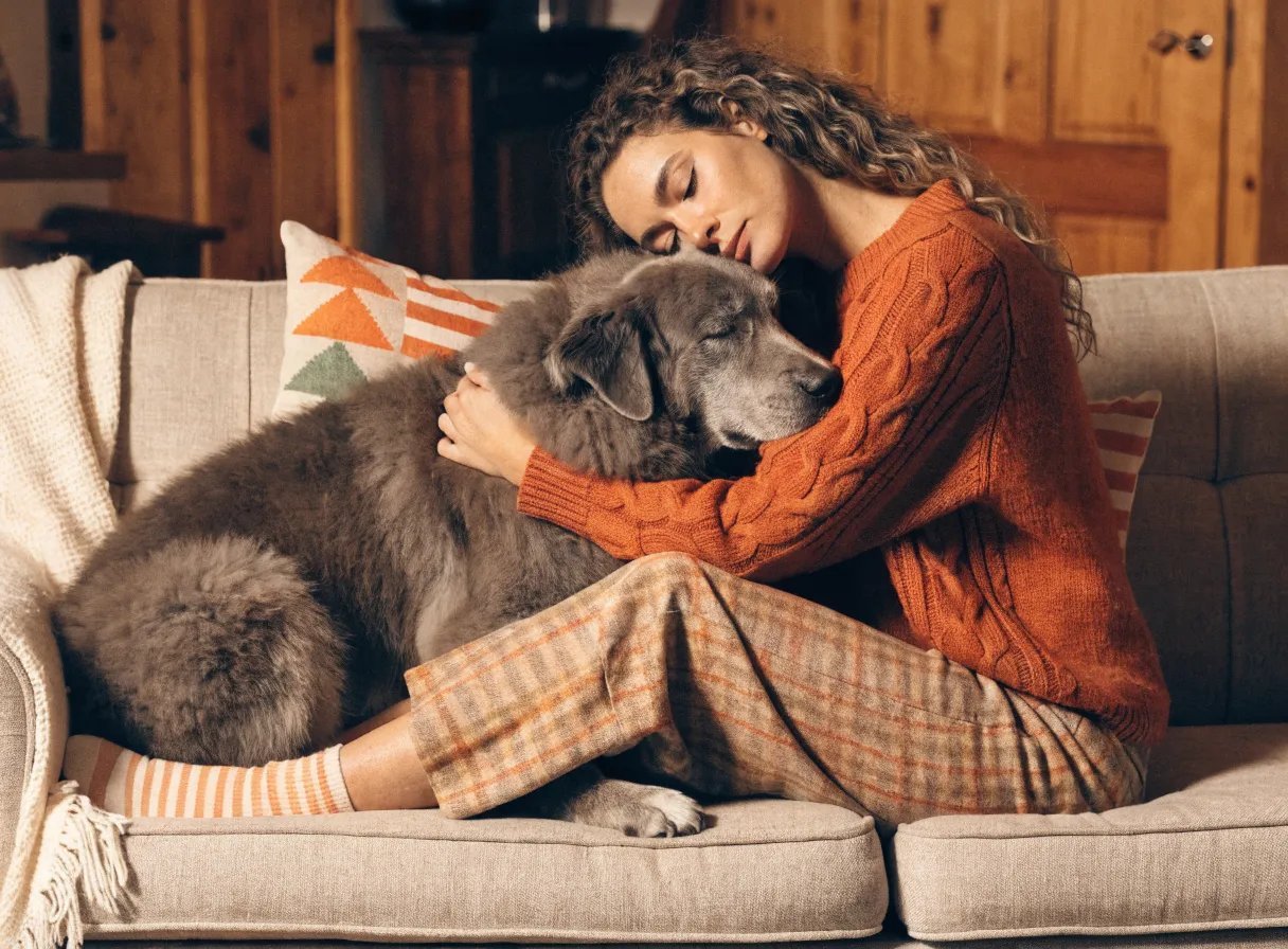 A person cuddling with a dog on a couch, portraying a strong bond.